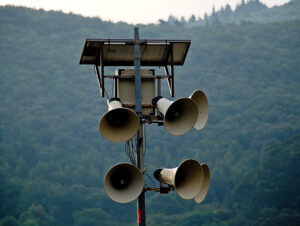 Photograph of a pole with six speakers.