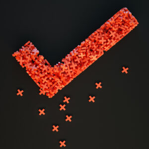 Photograph of a check mark made up of several red plastic "X's" on a black background.