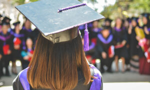 Photograph of a graduating student wearing cap and gown from the back.