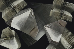 Fotografía superpuesta de varios libros con las páginas dobladas en forma de avión sobre un fondo negro infinito.