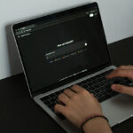 Photograph of a person typing on a laptop on a desk.