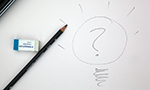 Fotografía de una hoja de papel en la que se dibuja a lápiz una bombilla con un signo de interrogación en su interior. En el lado izquierdo del dibujo hay un lápiz y un borrador.