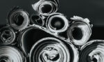Rolled sheets of paper arranged in a pile on a dark surface, black-and-white photo.