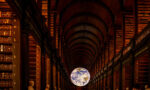 Fotografia de grande salão da biblioteca com livros e um globo de terra brilhante.